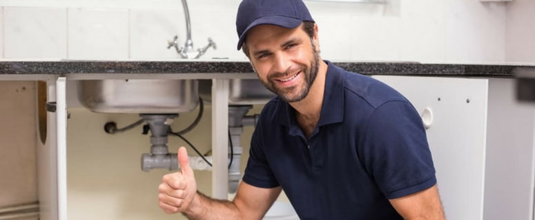 plumber installing garbage disposal in kitchen sink